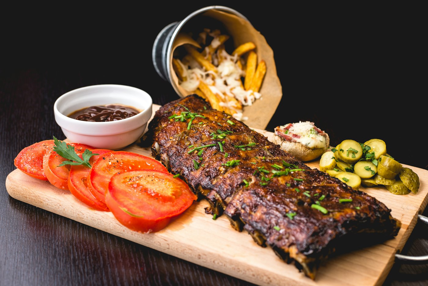 Costillar lacado con tomate y encurtidos sobre tabla